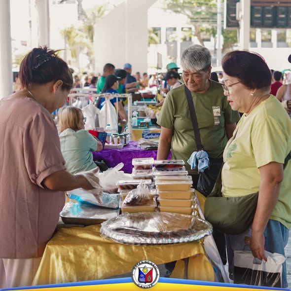 Mga mamimili sa Kadiwa ng Pangulo sa Naic Town Plaza habang tinitingnan ang mga paninda sa mesa