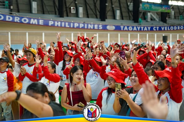 Masayang grupo ng mga tao na nagtataas ng kamay at nagchee-cheer sa Tagaytay City Velodrome