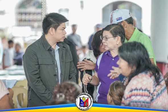 Mga tao sa validation ng National Social Pension sa Naic Town Plaza, may kausap na nakatatanda