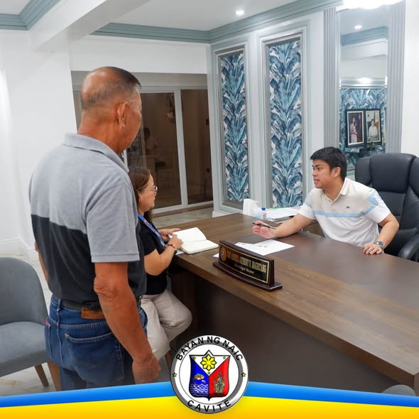 Mga tao sa opisina ng Naic Municipal Hall habang may kausap sa mesa