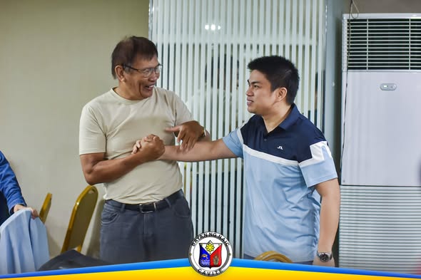 Dalawang lalaki na nagkukuwentuhan at nagtatawanan sa loob ng silid-pulungan sa Naic