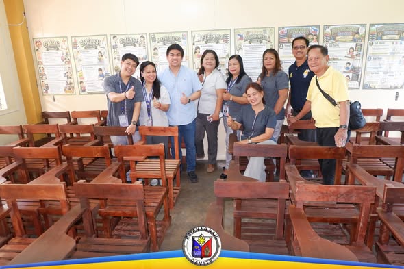 Grupo ng mga kawani habang nagpo-pose kasama ang mga bagong school chairs sa Halang Elementary School