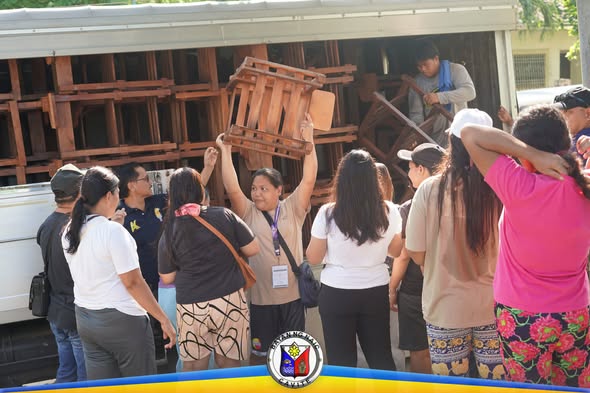 Mga tao habang inilalabas ang mga school chairs mula sa truck sa Halang Elementary School