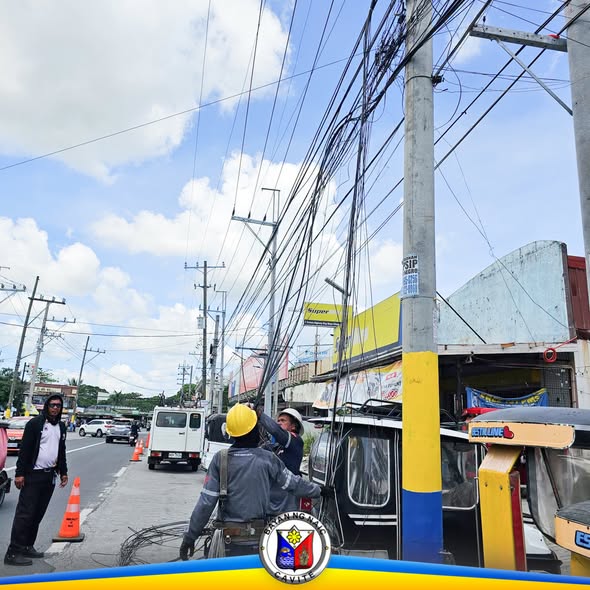 Mga manggagawa habang inaayos ang mga kable sa poste sa gilid ng kalsada, Ibayo Silangan, Naic