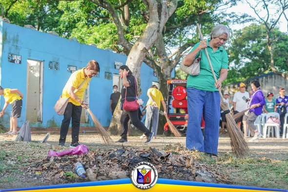 Mga senior citizen na nagwawalis at naglilinis ng mga tuyong dahon at basura sa tabi ng asul na gusali