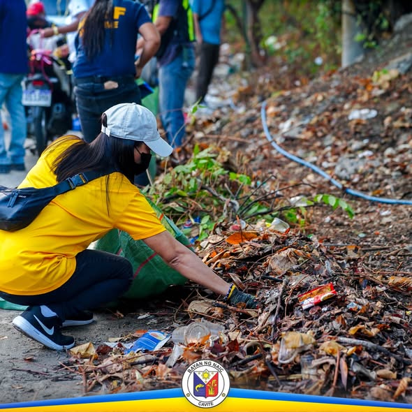 Litrato: Isang babaeng nagpupulot ng basura sa gilid ng kalsada habang naglilinis ang mga volunteers sa Friendship Road