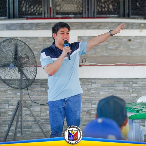 Lalaking nagsasalita sa mikropono at nagtuturo habang may pagtitipon sa covered court ng Naic