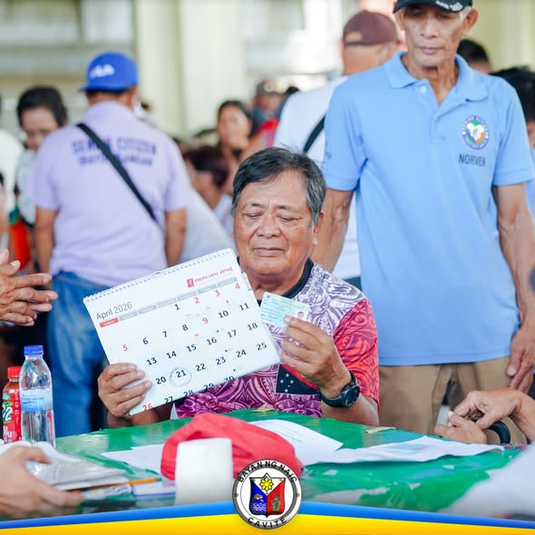 Matandang lalaki na hawak ang kalendaryo at card sa payout ng National Social Pension sa Naic