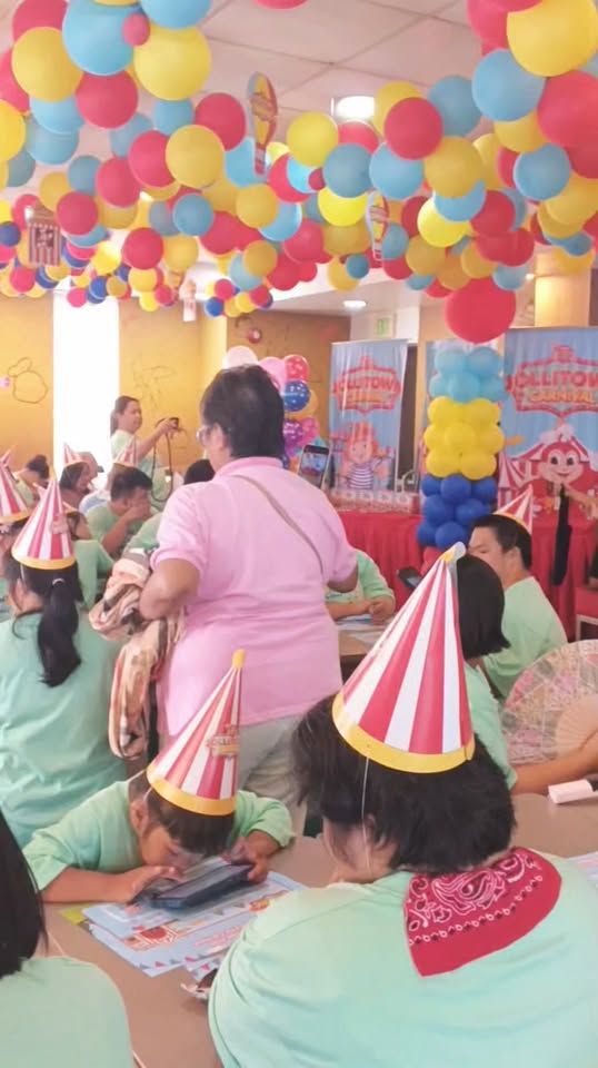 Mga kalahok na naka-party hat at berdeng t-shirt sa Lollitopia Carnival, National Down Syndrome Awareness Month