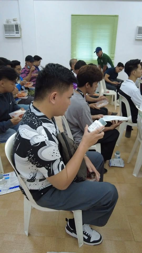 Mga kalahok sa Dengue Awareness Seminar na nakaupo at may hawak na pagkain at papel sa Amisa Medical Mission