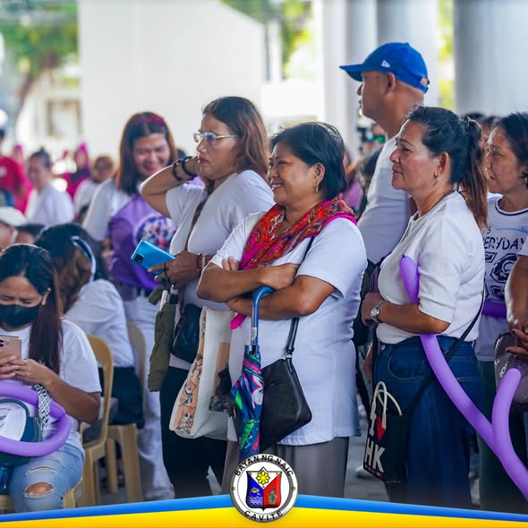 Mga kababaihan na nanonood ng pagdiriwang ng Women's Month sa Naic Town Plaza, may purple na balloons.
