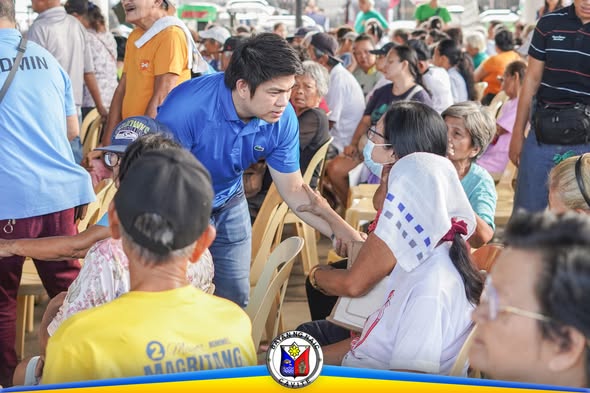 Isang opisyal na bumabati sa mga senior citizen habang namamahagi ng National Social Pension sa Naic Town Plaza