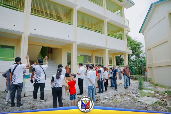Grupo ng mga tao na tumitingin sa bagong tatlong palapag na school building sa Timalan Hills View Integrated School