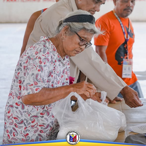 Matandang babae habang inilalagay ang bigas sa plastik na supot sa KADIWA Rice Selling sa Labac