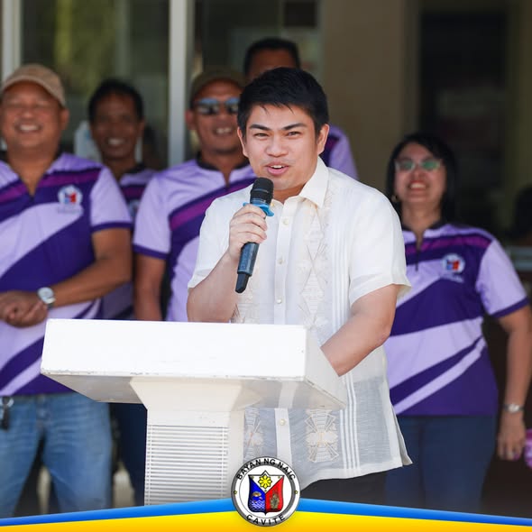 Lalaking nagsasalita sa mikropono sa podium habang nakikinig ang mga kawani ng LGU sa flagraising sa Naic