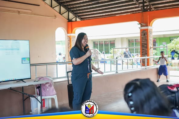 Babaeng tagapagsalita na nagbibigay ng orientation tungkol sa rabies sa covered hall ng paaralan sa Naic