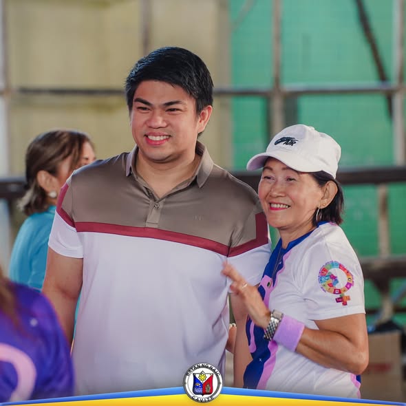 Dalawang tao na nakangiti sa Women's Wellness Fair sa covered court ng Naic