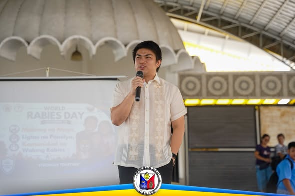 Lalaking nagsasalita sa mikropono sa World Rabies Day celebration sa Naic Town Plaza