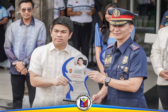 Ginawaran ng Plaque of Appreciation ang isang lalaki habang inaabot ito ng pulis sa seremonya sa Naic Municipal Hall.