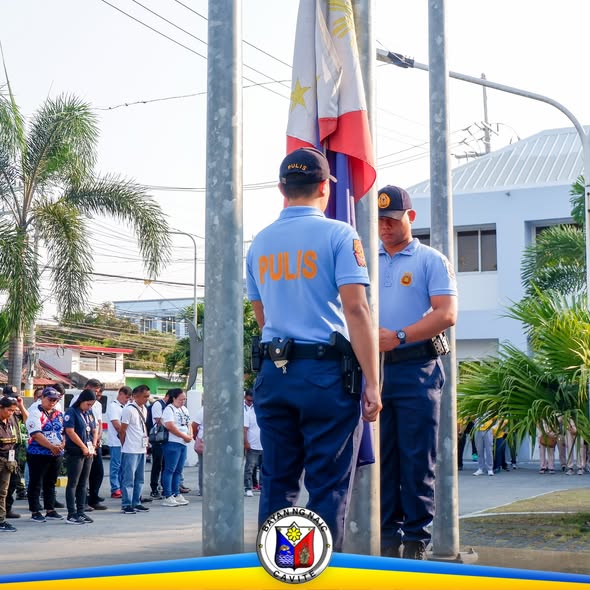 Mga pulis na nakatayo sa flag raising ceremony sa harap ng Naic Municipal Hall
