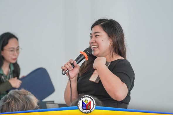 Babaeng nagsasalita sa mikropono habang nakangiti sa training ng financial literacy sa Sabang, Naic