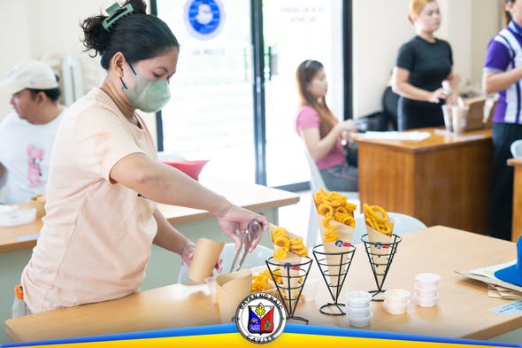 Babaeng nagsasandok ng curly fries sa paper cone habang may food tasting sa Liga ng mga Barangay, Naic