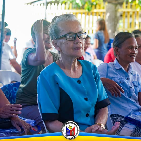 Mga miyembro ng kooperatiba na nakaupo at nakikinig sa General Assembly sa labas ng PARC Building, Naic