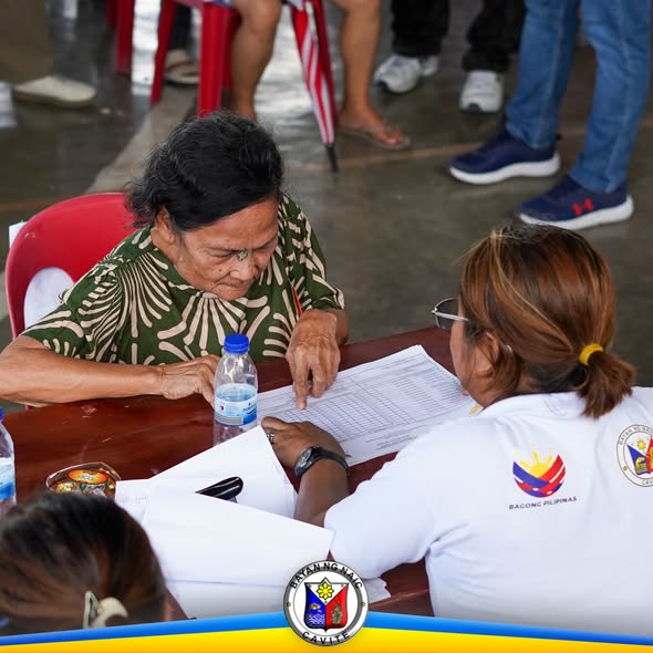 Matandang benepisyaryo habang sinusuri ang listahan kasama ang staff ng Localized Social Pension sa Sabang