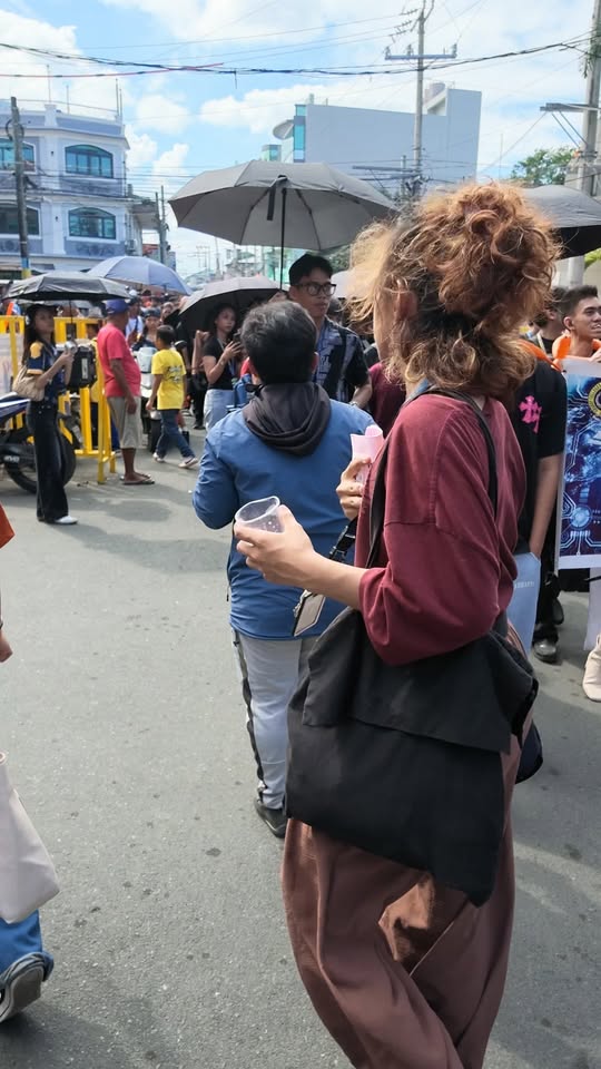 Mga tao naglalakad sa kalsada habang may hawak na plastik na baso at papel sa Sportfest ng Granby Colleges.