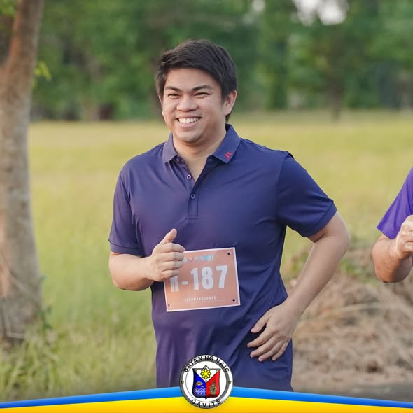 Kalahok sa Takbumbero 2026 na nakangiti at nagthumbs-up habang may suot na race bib sa parang