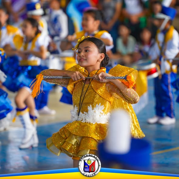 Batang nagpe-perform na naka-gintong kasuotan at baton sa Cheer Chant Competition sa Naic Covered Court
