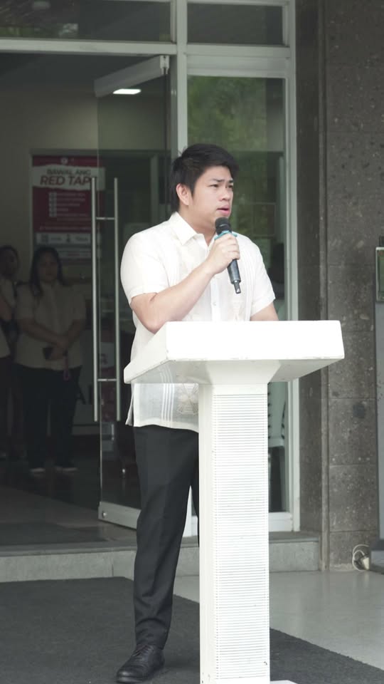 Lalaking nagsasalita sa mikropono sa podium sa harap ng gusali, pasasalamat sa mga rescuer sa Malainen Luma