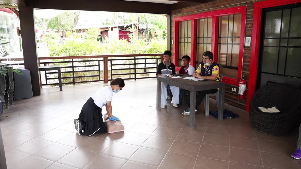 Nagsasanay ng CPR sa manikin sa veranda ng Torres Farm Resort, Barangay Sabang, habang nanonood ang mga kasama.