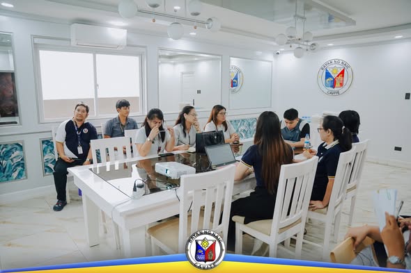 Mga kalahok sa pulong ng Local School Board habang nakaupo sa paligid ng mesa sa Naic Municipal Hall