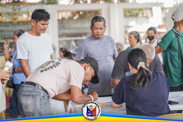 Mga kalahok na nag-aasikaso ng papeles sa mesa habang nagpapalista sa Info-Caravan sa Naic Covered Court
