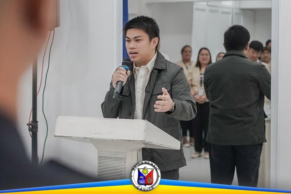 Lalaking nagsasalita sa mikropono sa podium during Flag Raising Ceremony sa Mayor's Office, Naic