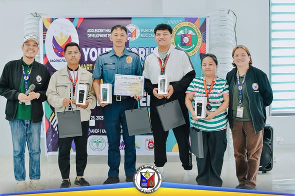 Mga kalahok ng Youth Forum na nagpapakita ng premyong cellphone at certificate sa harap ng banner