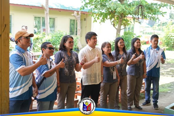 Grupo ng mga opisyal at kawani ng LGU Naic na nagpo-pose at nagthumbs up sa labas ng gusali