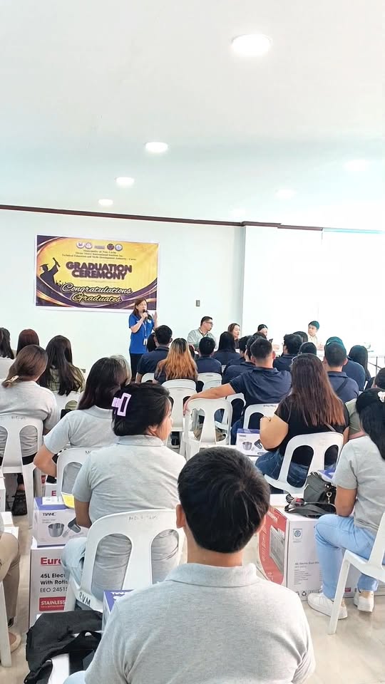 Graduation ceremony ng TESDA sa Triple 8 Bldg., Sabang, Naic; nagsasalita ang isang host sa harap ng banner
