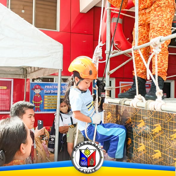 Estudyante na umaakyat sa rope course habang pinapanood ng mga bumbero at kapwa estudyante sa Naic Fire Station