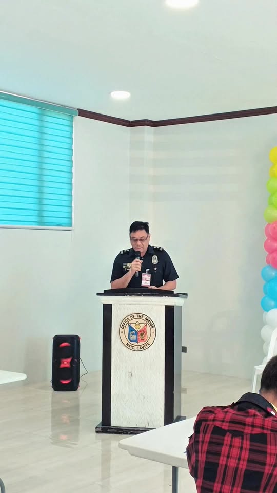 Litrato: Opisyal ng BFP na nagsasalita sa podium sa canvas painting contest sa Triple 8, Sabang, Naic