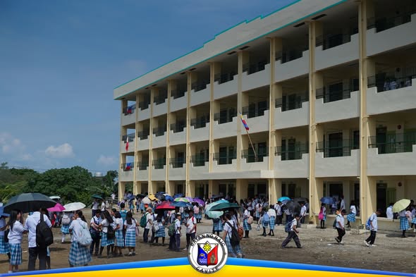 Mga estudyante sa Timalan Hillsview Integrated School Annex na may payong sa labas ng gusali ng paaralan