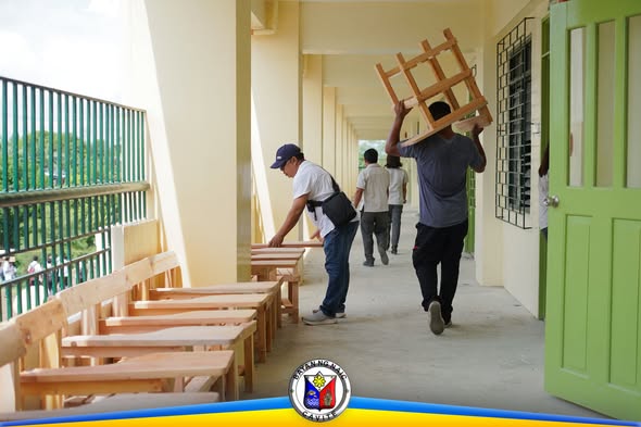 Mga kalalakihan na nagdadala ng bagong upuan ng paaralan sa koridor ng Timalan Hillsview Integrated School Annex