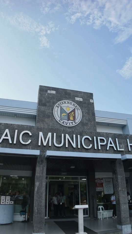 Harapan ng Naic Municipal Hall na may selyo ng Bayan ng Naic, Cavite, at ilang taong nasa pasukan