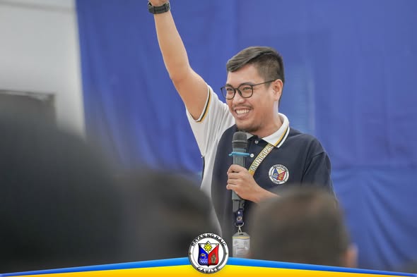 Isang lalaking nagsasalita sa mikropono habang nakataas ang kamay sa training ng nutrisyon at kalikasan