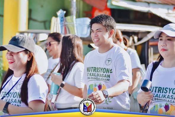 Mga kalahok sa Nutri Walk na naka-puting t-shirt na may islogang Nutrisyon at Kalikasan habang naglalakad sa kalsada