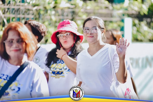 Mga kalahok sa Nutri Walk na kumakaway habang naglalakad sa labas, bahagi ng 52nd Nutrition Month sa Naic