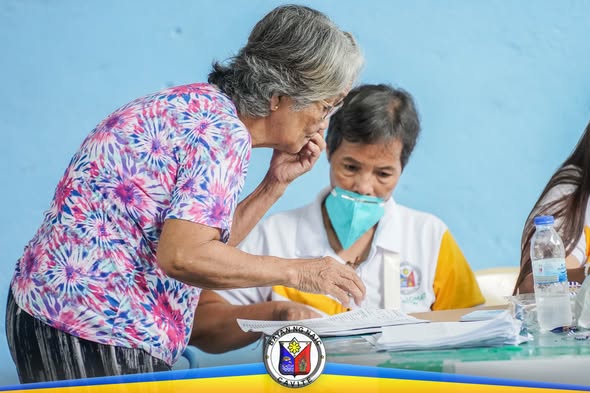 Matandang babae habang inaasikaso ng staff ng MHO sa PhilHealth YAKAP para sa Manggagawa sa Timalan Concepcion
