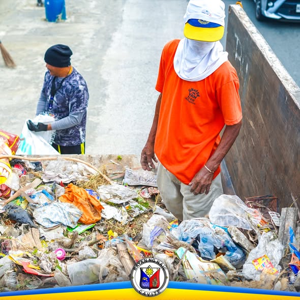 Mga volunteer na naglilinis ng basura sa gilid ng highway ng Muzon, Naic, habang nakasakay ang basura sa truck