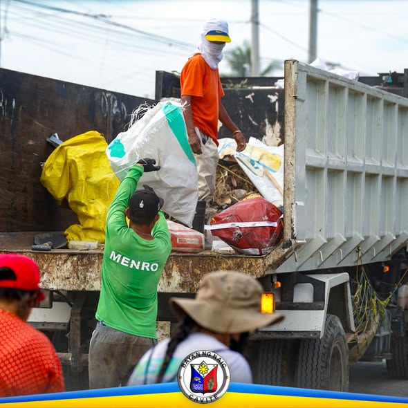 Mga tauhan ng MENRO habang inilalagay ang mga basurang sako sa trak sa Clean-Up Drive sa Muzon, Naic